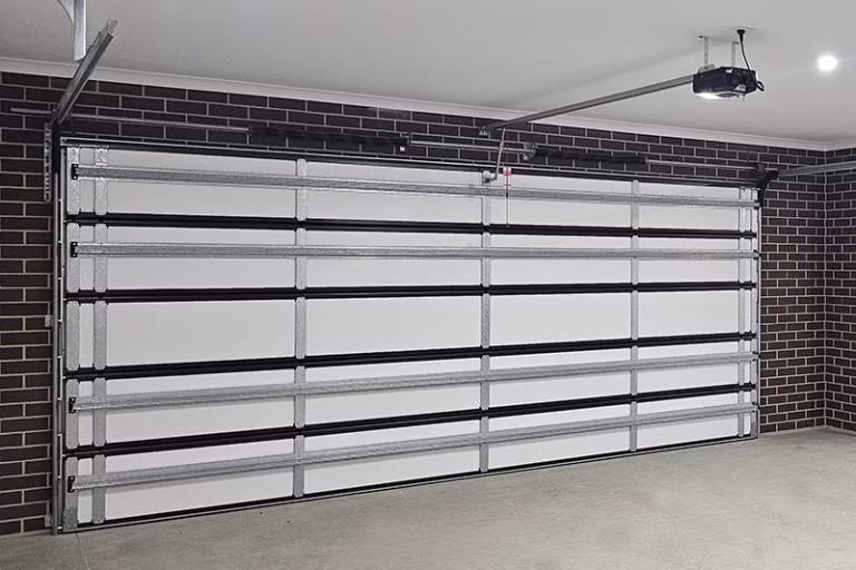 Interior view of a sectional garage door installation with insulation and an automatic opener motor in a Shepparton home.
